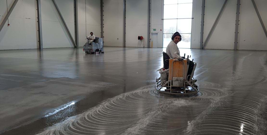 två män utför diamantslipning på betonggolv