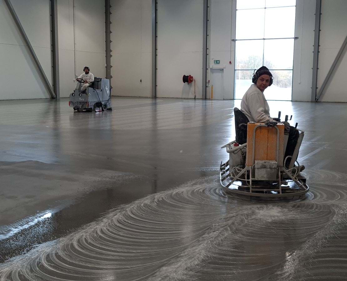 två män utför diamantslipning på betonggolv