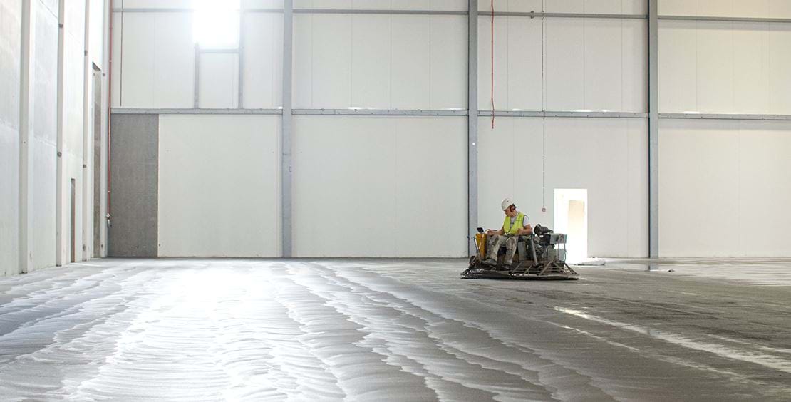 Man på glittermaskin utför Teqplan-processen för lagergolv